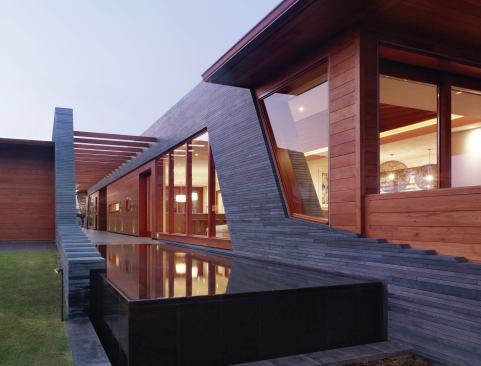 The far end of the entry corridor tips gradually into an infinity pool. The various pods are made of recycled teak railroad ties and indigenous stacked basalt.