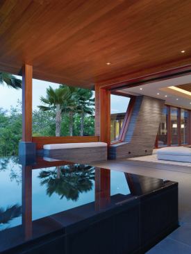 Glass walls dematerialize, encouraging indoor-outdoor living. Outside the living room, a pool constructed of basalt lava rock reflects the sky.