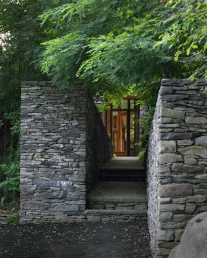 A deliberately narrow walkway between the parking area and the house creates a sense of compression that is released by the openness of the interior.