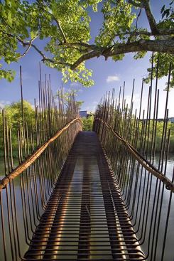 The foot bed and railings are formed by bent rebar, cut to random lengths and tightly spaced to blend with the reeds that grow along the shore. A rope handrail is secured with steel wire rings to the horizontal bar welded to the vertical bars.