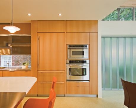 A new kitchen in existing space segues seamlessly to a casual dining area, which opens to a wooded yard via nesting glass sliders. 