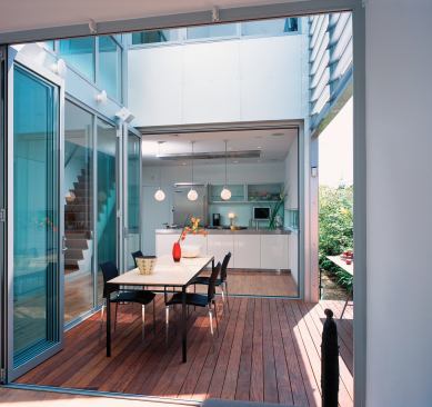 Sight lines from the kitchen and bath into other rooms expand the perceived size of both spaces. Prodema, a resin-bonded cellulose product with a natural wood veneer, tops the dining table.