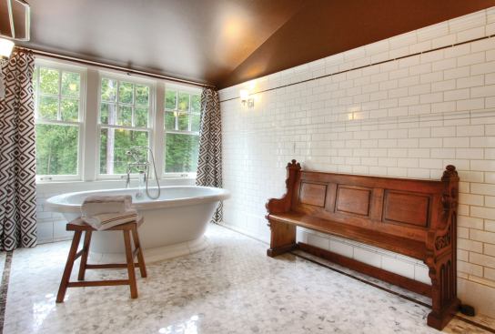 The bath's hexagonal floor tiles and freestanding tub evoke a retro feeling.