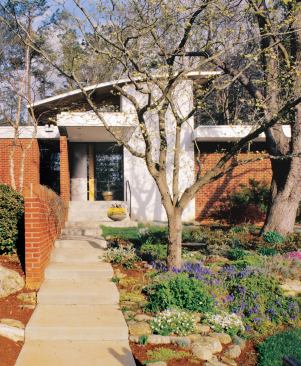 While a one-story frame keeps the house in context with its low-slung neighbors, its distinctive curved roof hints at the dramatic interior spaces.