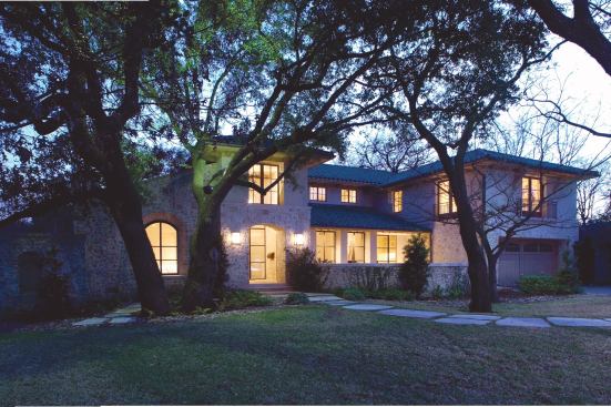 A low roof pitch and secondfloor setback let the home slip gently into its shaded site.