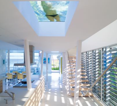 Deep skylights beneath a rooftop lap pool illuminate the open kitchen. Metal sunshades on the western side of the house create a dappled effect throughout the interiors.