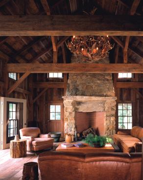 The outbuilding's rustic elements include a hand-distressed timber-frame structure, reclaimed pine paneling and floors, and a massive stone fireplace.