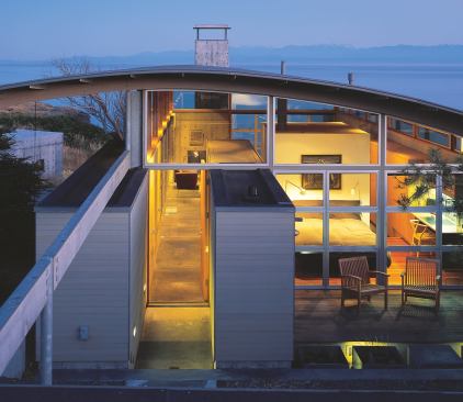 Broad expanses of glass reveal the architectural assemblies of the main house—roof, walls, chimney mass—as nearly free-floating elements.