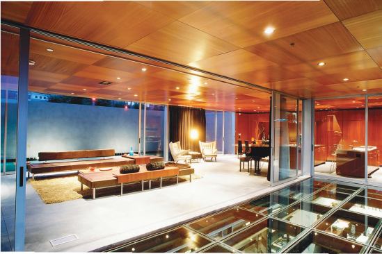 First-floor living spaces spill out into protected courtyards, and onto a glass patio that roofs the owner’s basement- level architecture studio.