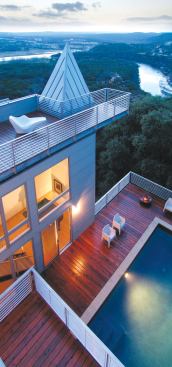 The multi-level house opens up toward the pool deck, with windows and balconies that overlook the space from several angles.