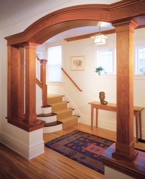 A cherry-trimmed, arched opening breaks off a new entrance hall from the existing living room, which boasts a new suit of period millwork, also in cherry.