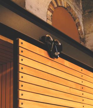 A second beam—with stock industrial hardware—serves as the track for the sliding panels that conceal the television.