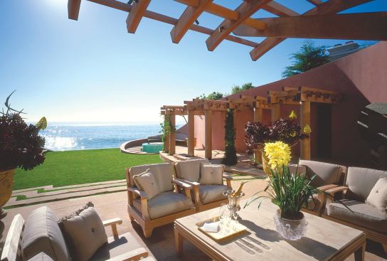 A dramatic teak trellis provides shade and defines the area of this outdoor room from above, while a random-pattern Arizona flagstone terrace leads from the living room down to the lawn and sculpture garden.