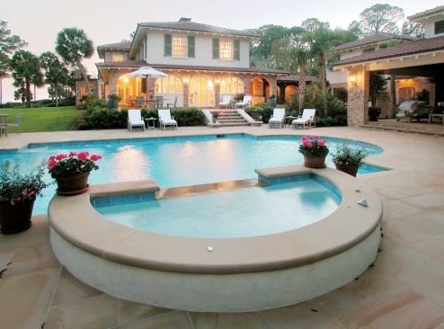 The rounded ends of the gunite pool give it a classical look well suited to the stately old house. From the kitchen, the clients can see the spa with its spilling waterfall.The spa is capped with sandstone to match the terraces and pool deck.