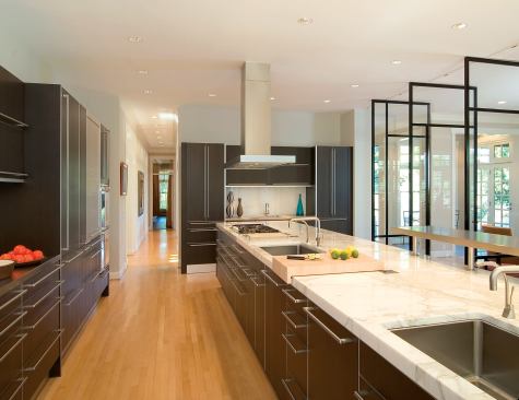 Oriented to the family room, the kitchen island functions for working and entertaining, and "its length also provides an axis of visual drama within the space," architect Bob Gurney says.