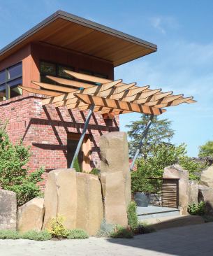 A wall of basalt boulders gives the house a measure of privacy. The entry tower, trellis, and copper-sheathed bay window help define the front façade.
