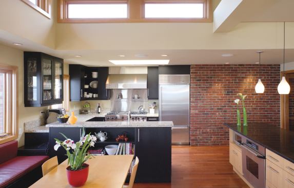 Clerestory windows bestow generous natural light on the interiors. An exposed brick wall in the kitchen pays tribute to the original house.