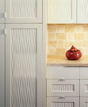 The undulating cabinet fronts in this Seattle kitchen contrast with the rough texture of plaster backsplash tiles.