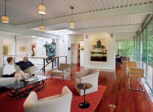 Glass curtain walls float within the structural cube, leaving a narrow covered deck around much of the perimeter.