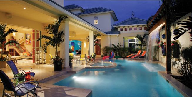 The pool is the main attraction of this playful courtyard. Travertine decking wraps the edge and top 8 inches of the gunite pool, for a clean, crisp look. Level with the water, the travertine-topped wall that forms the spa also serves as an aquatic bar that is complete with underwater stools. At the far end of the pool, stepping pads lead across the water to a small lounging area.