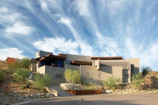 The cul-de-sac's center point inspired the radius for the house and retaining walls. The concrete masonry provides both structure and finished surface. From inside, the rotated block creates an aperture to the outdoors and a filter for light.