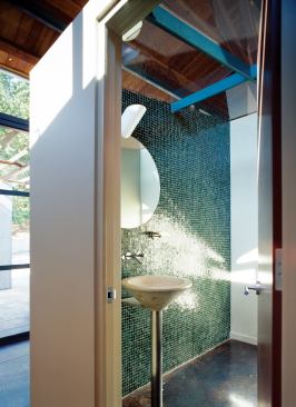 In the powder room, a wall of glass mosaic tile adds glitter, and compact circle-themed fixtures and fittings take care of business with minimum fuss.