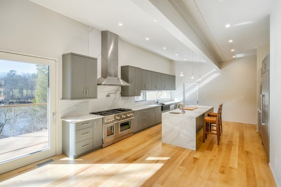 A 20-foot, Passive-house-rated sliding glass door provides a panoramic view of the river from the main living space. The steel beam that supports the gently sloping butterfly roof is exposed in the open floor plan. 
