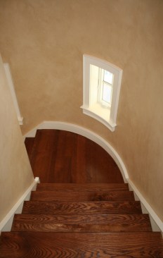 Shot before the rails went in, this photo shows that client didn’t want a grand, curved stair. Instead, the stair is tucked off to the side. It's 4 feet wide, and the flooring and treads are white oak. The walls are painted in a faux finish meant to resemble limestone, and the back stair was done in a similar fashion. 