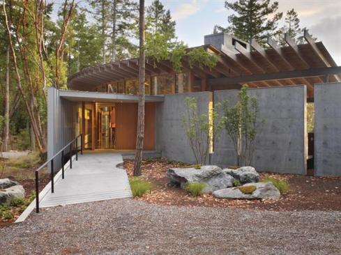 A zinc-clad wall peels away from the house's curving concrete flank to form the entry.