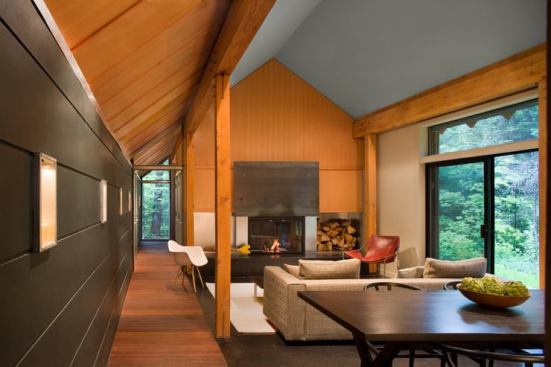 The building's two halves mirror each other; each offers a fireplace and a wall open to views of the forest meadow. During winter, the interior living rooms become the primary living spaces, while the courtyard reigns supreme during the warmer months.