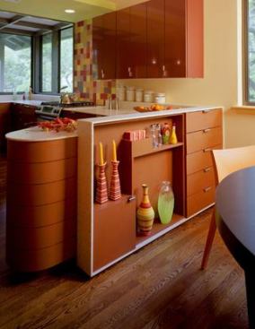 Stained 'Extira" MDF cabinets, recycled wood floors, and simple solid-surface countertops establish a warm color foundation. The upper cabinets' high-gloss/auto-finish laminate, the multi-colored glass tile over the backsplash, and the gala-apple ceiling soffit compliment one another.