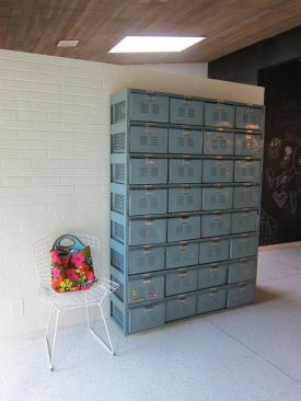 Blue metal drawers add a touch of color to the white brick wall that screens off a work station/sewing desk.