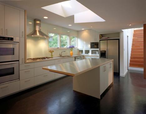 Some backsplashes are so dramatic they can’t help being the center of attention. Others take a quieter supporting role, such as the sleek vent hood wall in this renovated mid-century modern house by Alterstudio Architects. “The backsplash is a monolithic piece of glass that has been painted on one side. The painted side of the glass faces the wall, while the non-painted side faces outward,” the architects explain. “We used the same paint as the walls and a continuous bead of silicone around the perimeter of the glass to attach it to the wall. Using a white paint on standard glass gives a slight green hue due to the natural color of glass.” Sleek and relatively inexpensive, this solution is easy to clean (there are no seams or grout lines) and gives the wall an unusual feeling of depth. 
http://alterstudio.net