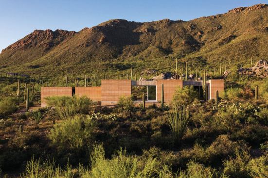 The rammed earth house blends into the desert landscape, turns its back to the east and west, and collects southerly views and solar rays.