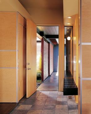 Charcoal gray siding and red accent walls jazz up the homes exterior. A continuous bench running right through the entry wall, below, helps knit inside and outside together.