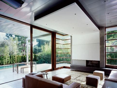 Home theater speakers are concealed behind a family room soffit. The soffit becomes a striking design detail as it drops down over the fireplace to supply a screen surface for a built-in projector.
