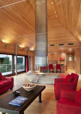 The central pavilion, which contains the kitchen, dining, and living spaces, projects over the pond, carrying at its center a 12-ton boulder that serves as the fireplace hearth. 
