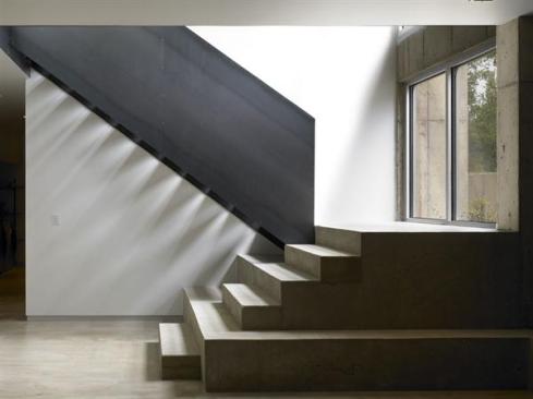 A steel-and-concrete stair adds sculptural interest at the lower level.