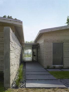 A board-formed concrete wall leads visitor to the entry and extends through the house.