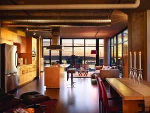 Interiors feature 10-foot ceilings, exposed ductwork, concrete pillars and killer views of the city. A subterranean garage includes reserved parking for bicycles and flex cars, along with stormwater management and CO2 monitoring systems. Builder: JE Dunn Architect: Mithun Developer: The Schuster Group