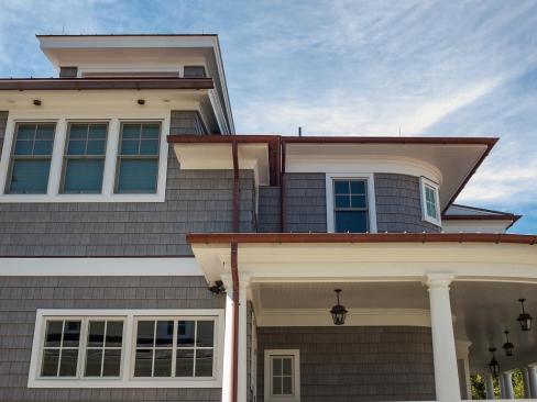 Copper gutters are a detail that’s common to the area—as is standing seam copper roofing—so it was logical to install half-round gutters with circle-type hangers. With the salt air, the roof and gutters will turn green eventually, but it will take decades.  