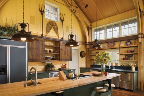 Moss-green cabinets and bright yellow painted-wood walls provide a polished backdrop for rustic touches, such as rough-cut wood planks on barn-like sliding cabinet doors.