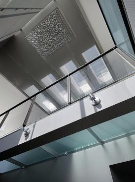 A lower-level vantage point shows the kitchen’s skylights, hanging sculpture, and glass floor.