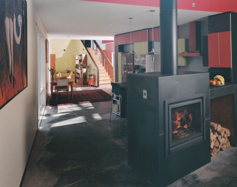 The chimney of the original house was dismantled and the brick was used for a walkway and landscaping. In the kitchen, the new freestanding wood-burning Bodart & Gonay fireplace was finished with salvaged chalkboard