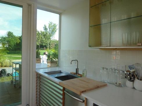 Galvalume-clad kitchen cabinets mimic exterior siding and extend seamlessly through the translucent wall to further augment an indoor-outdoor link.