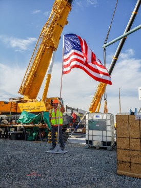 Joe Wheeler, architecture professor and lead faculty of FutureHAUS Dubai, holds an American flag at the Dubai competition site. Wheeler previously led a team to a first-place win in the international Solar Decathlon Europe with a home known as the LumenHAUS.