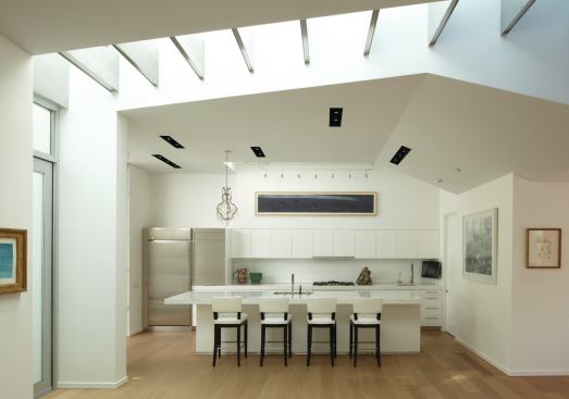 As it passes through the house, the pathway is defined by a linear skylight punctuated by aluminum-clad beams.