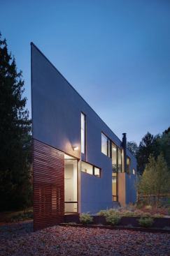 A screen of mahogany slats partially encloses the entry porch at the building’s knife-edge corner.