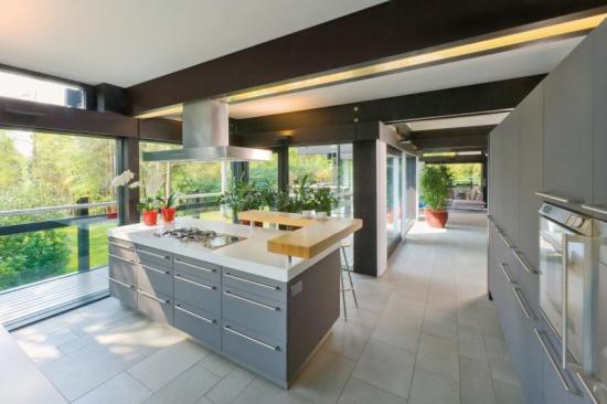 Natural sunlight beams through floor-to-ceiling triple-glazed windows onto rooms throughout the Huf Haus kitchen.