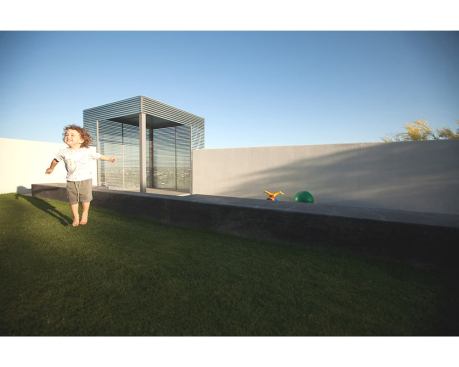 A strip of turf separates the sunken play area from the house.